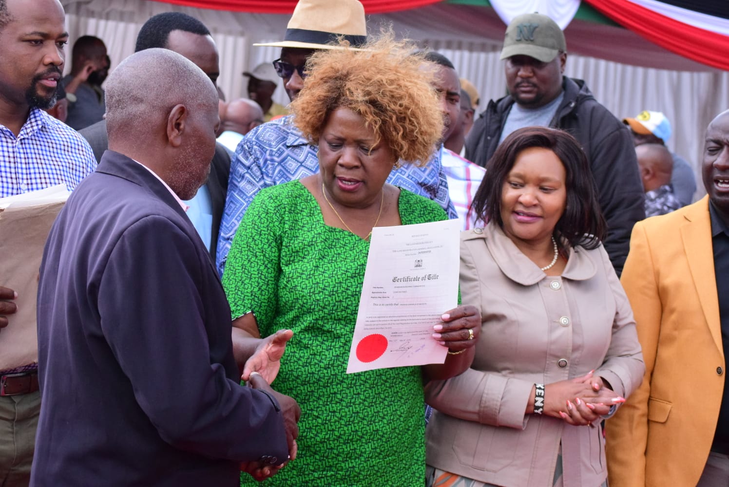 Lands Cabinet Secretary Alice Wahome (centre) hands over a title deed to a beneficiary in Ol Kalou, Nyandarua County. She issued 2,700 title deeds to residents of the area
