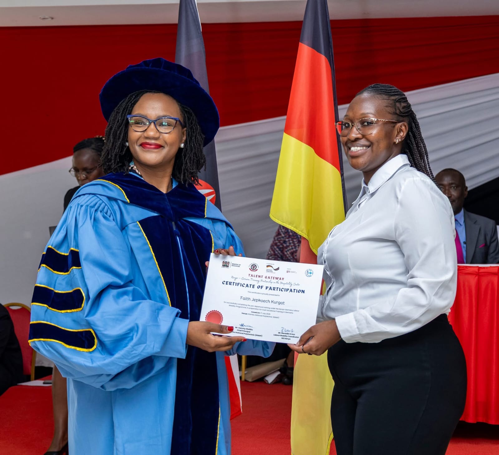 Principal Secretary for Diaspora Affairs Roseline Njogu (Left), awards a certificate to a graduand from Kiambu National Polytechnic.