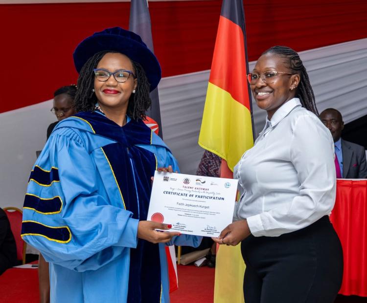 Principal Secretary for Diaspora Affairs Roseline Njogu (Left), awards a certificate to a graduand from Kiambu National Polytechnic.